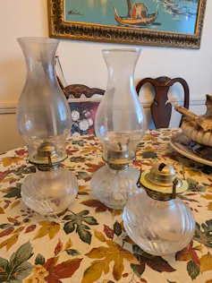 Three oil lamps sit on a table.