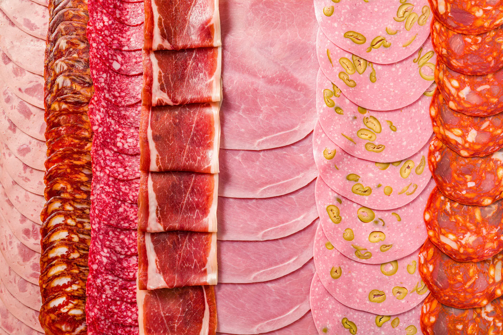 old cuts meat charcuterie slices in a row with pepperoni, chopped, ham, dry-cured prosciutto and chorizo, full frame