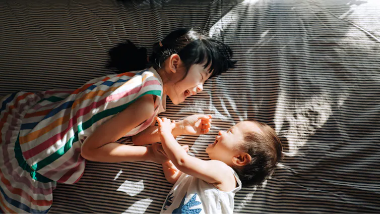 A toddler tickling a baby