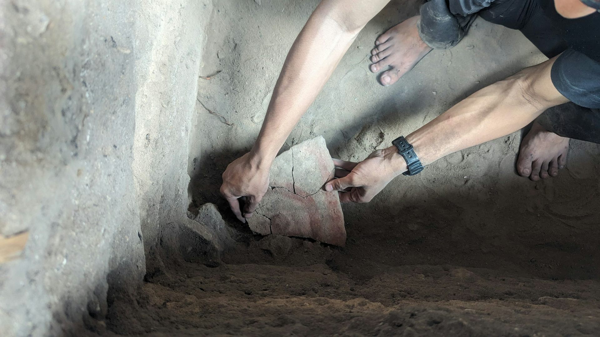 A person holds a rock fragment with an ancient rock painting.
