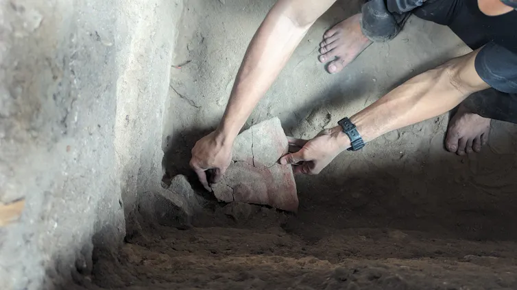 A person holds a rock fragment with an ancient rock painting.