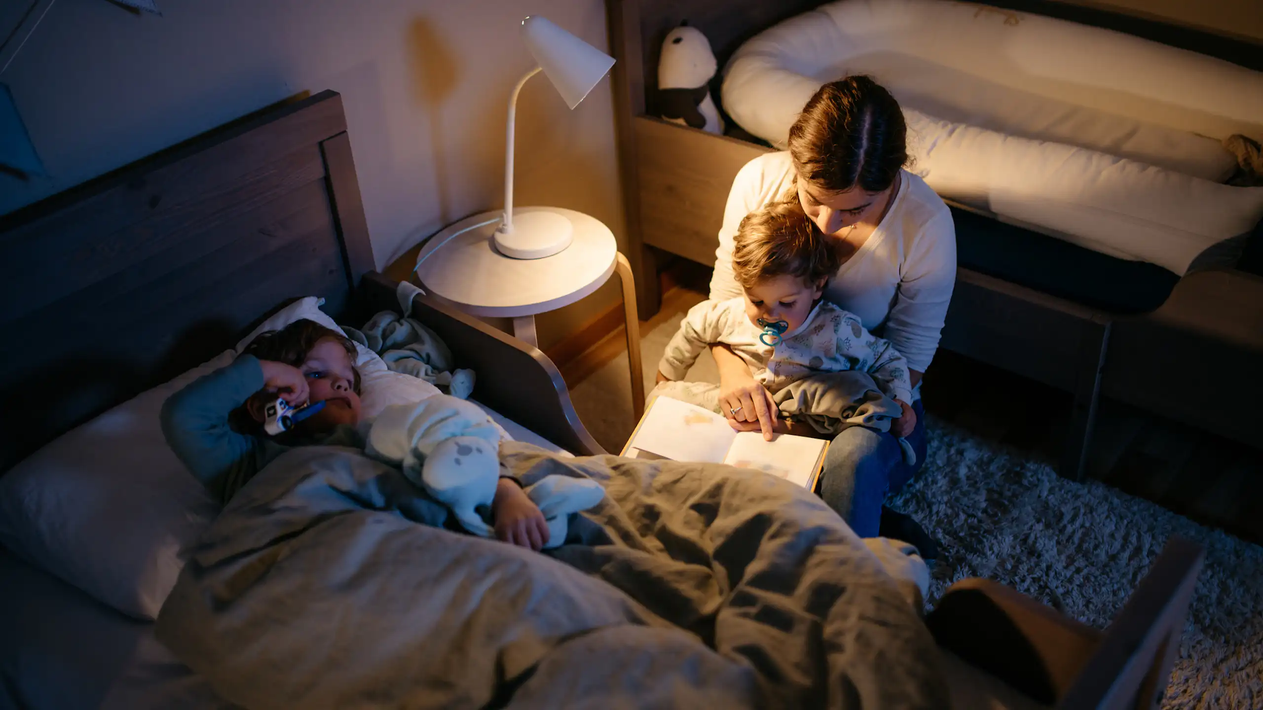 A young mother reads a book to her two sons before bedtime.