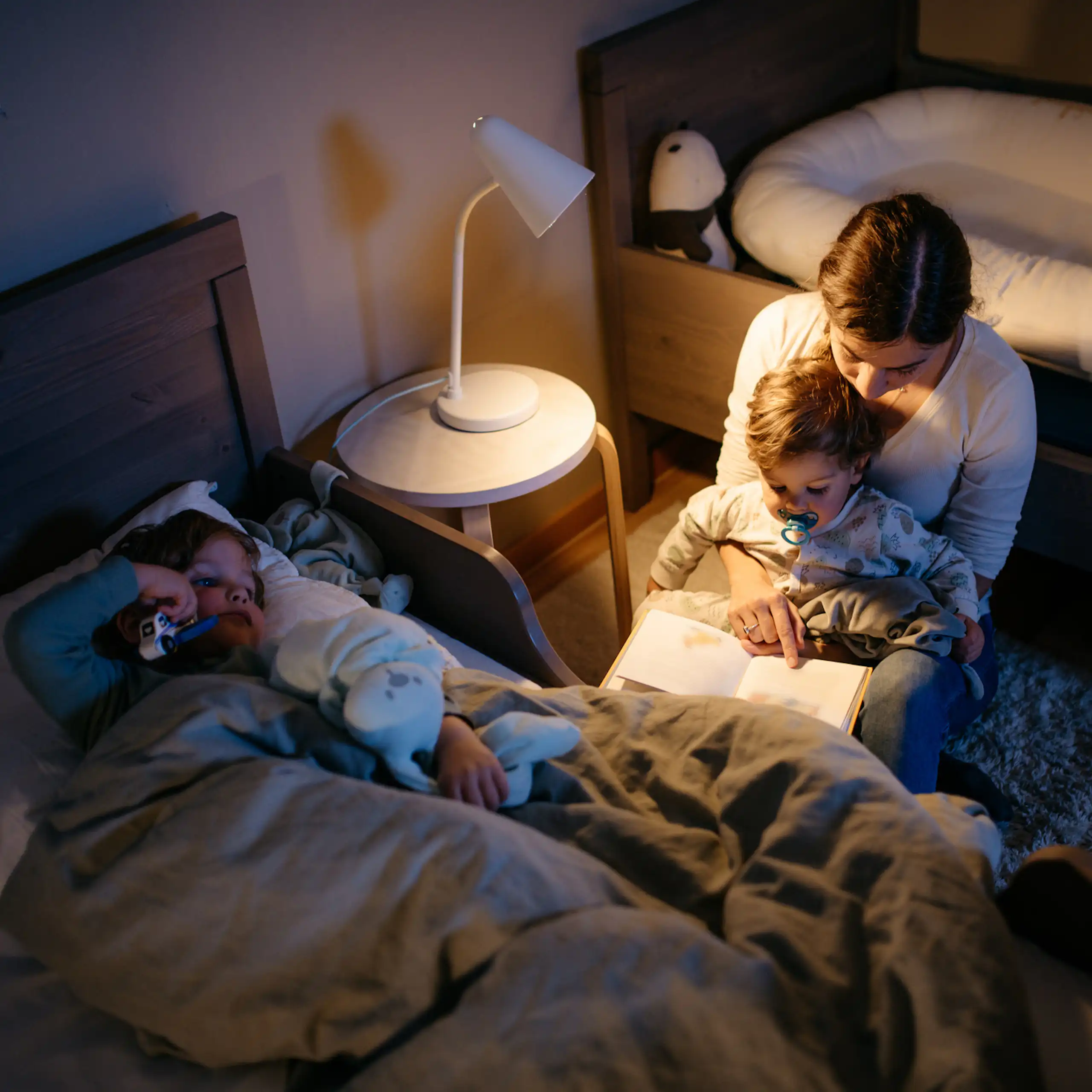 A young mother reads a book to her two sons before bedtime.