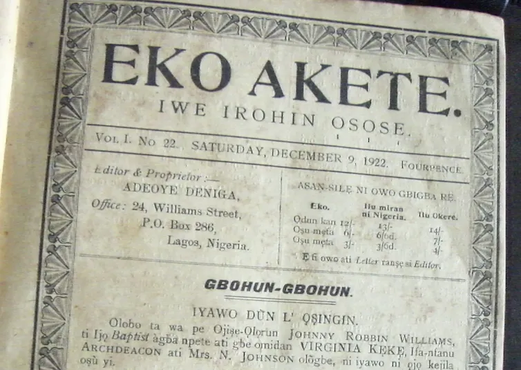 A black and white photo of a vintage newspaper with an ornate border, printed words and the title 'Eko Akete'.