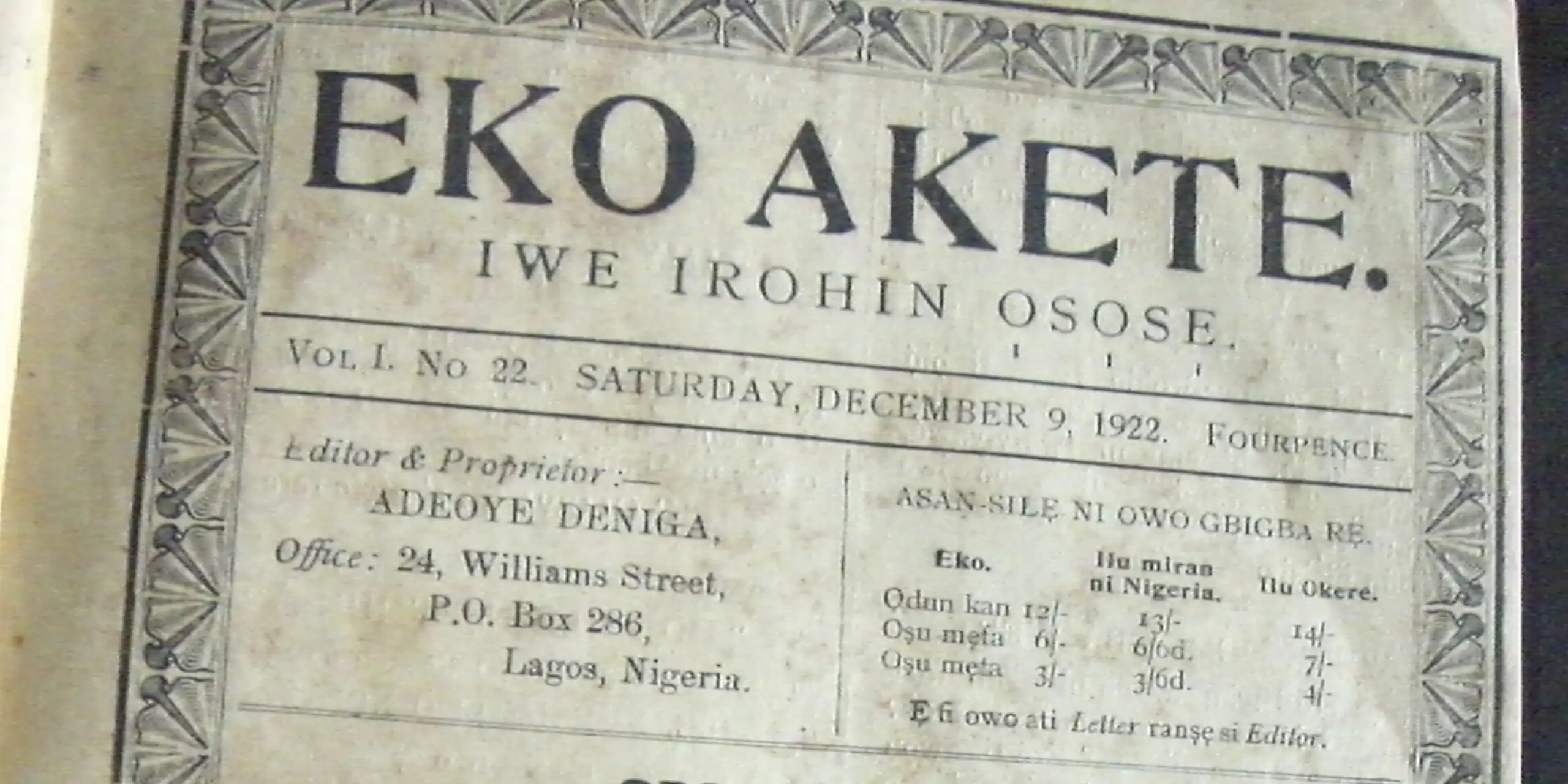 A black and white photo of a vintage newspaper with an ornate border, printed words and the title 'Eko Akete'.