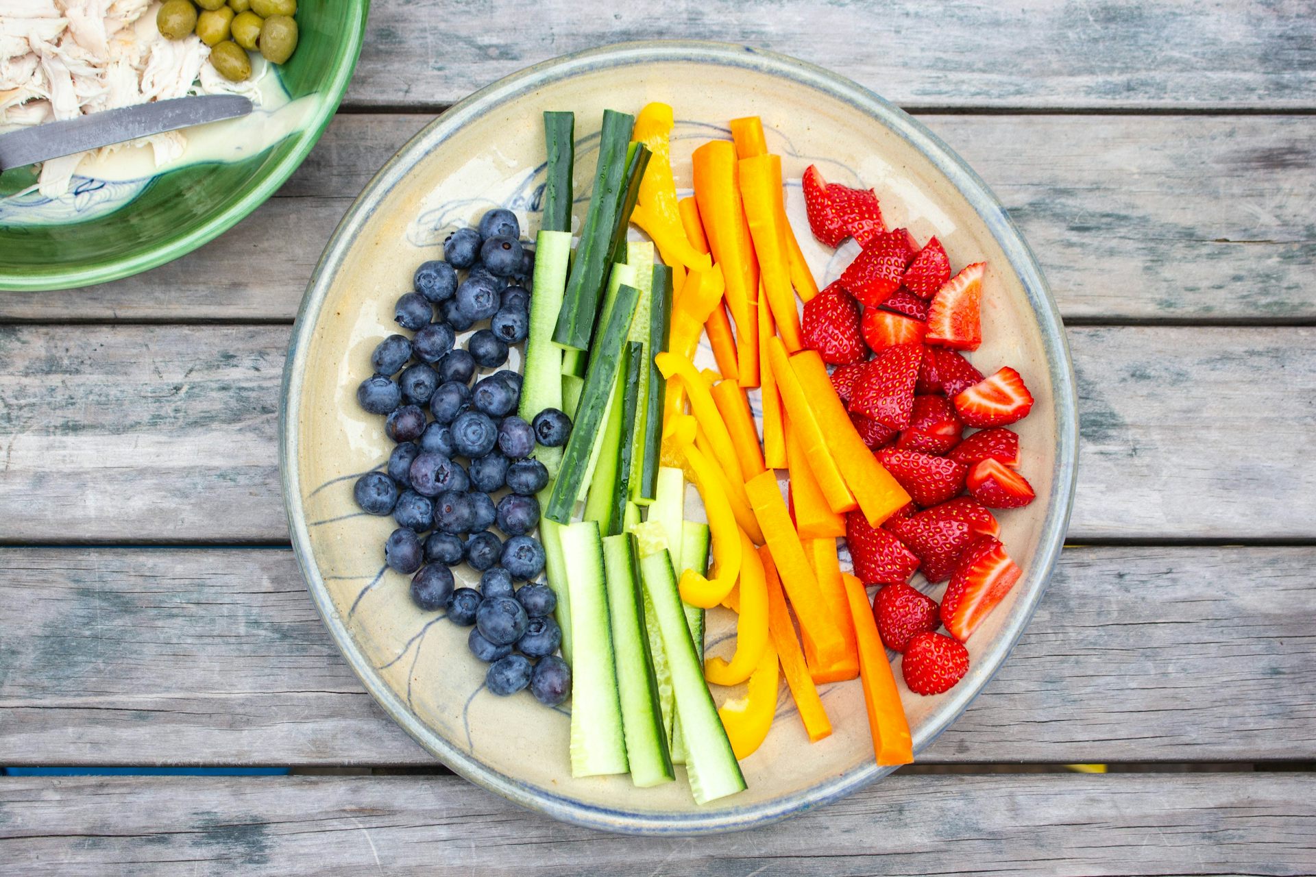 Close up of a plate of brightly coloured fruit and vegetables cut up for a child's snack