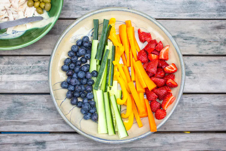 Close up of a plate of brightly coloured fruit and vegetables cut up for a child's snack