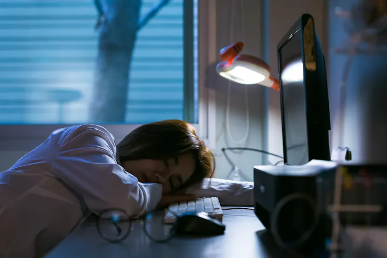Exhausted student sleeping at desk at night