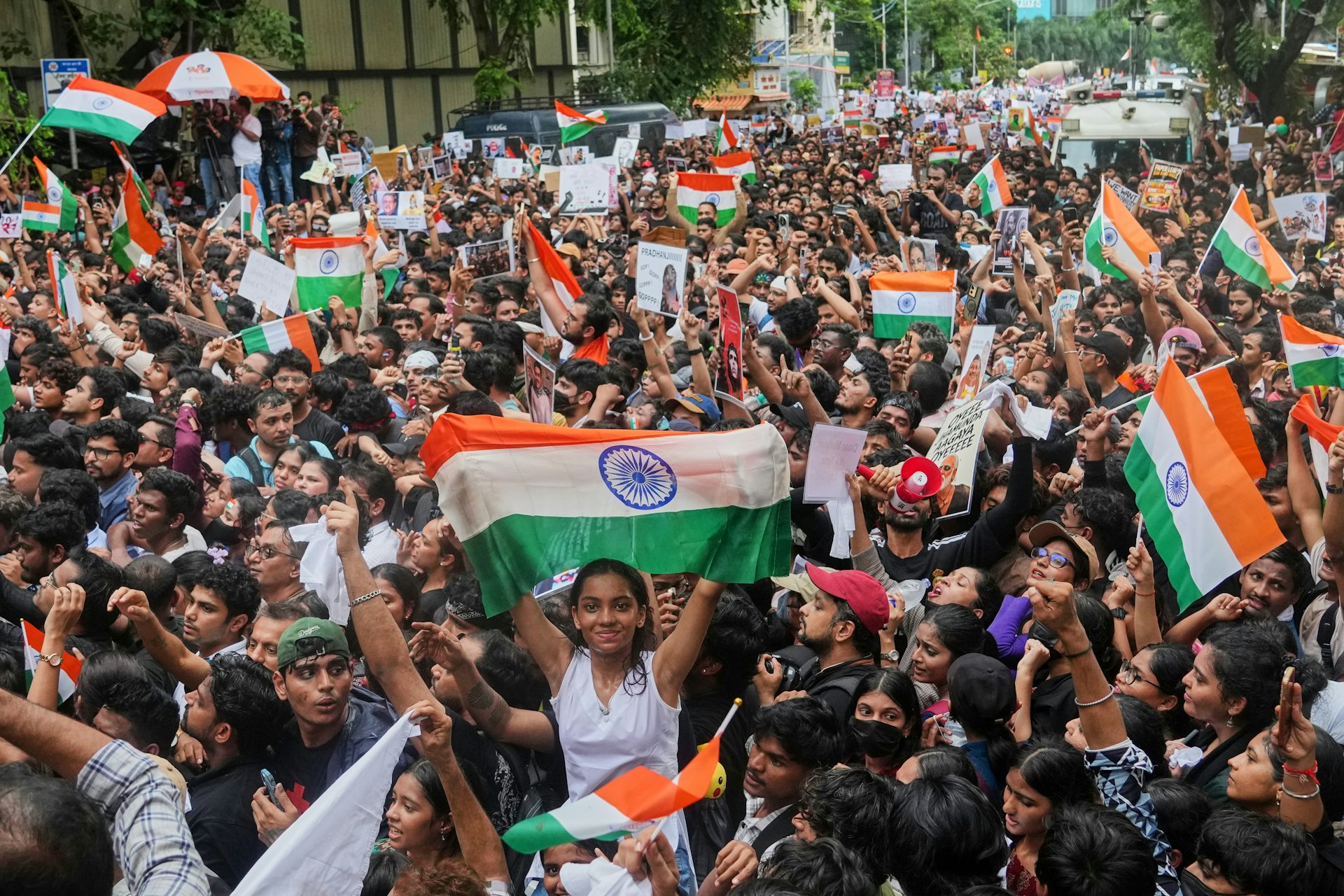 A large group of protesters holding up flags and signage as they chant.