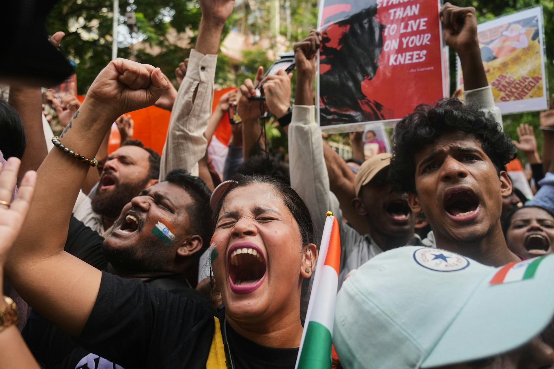 A closeup of the faces of a handful of protesters who are chanting and holding fists up in the air.