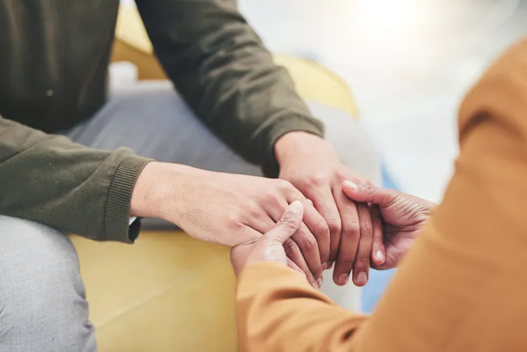 Close up of two people sitting and holding both hands with each other