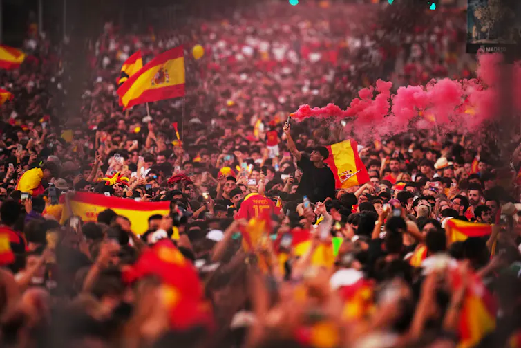 a large crowd of people cheer and wave spanish flags