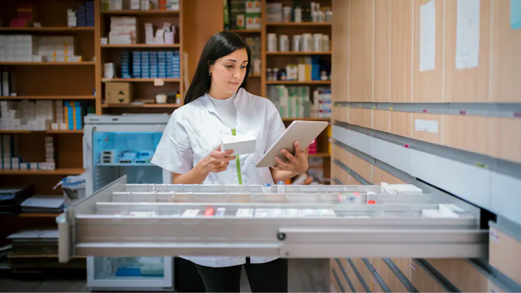 A pharmacist cross-checks stock with the information on a tablet