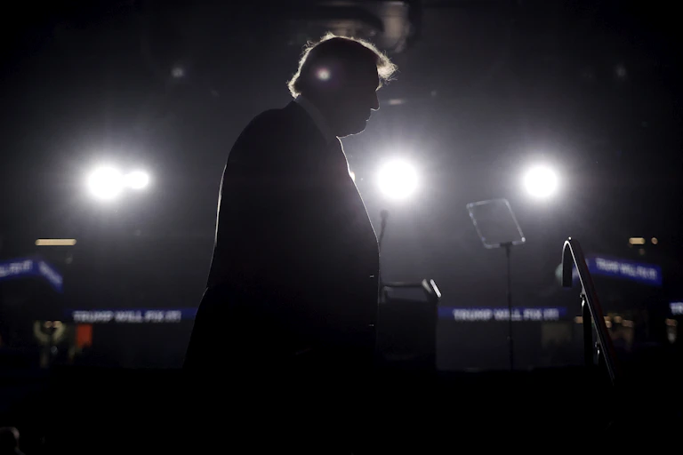 The silhouette of Donald Trump against bright media lighting