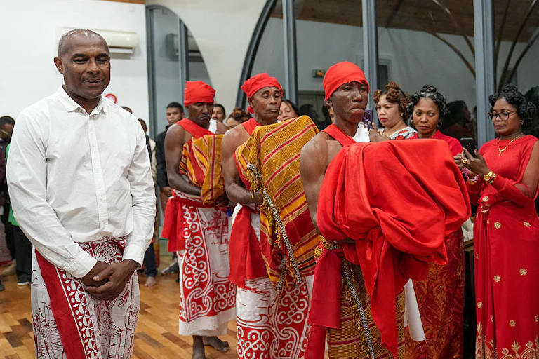 Three men carry draped bundles while other people look on