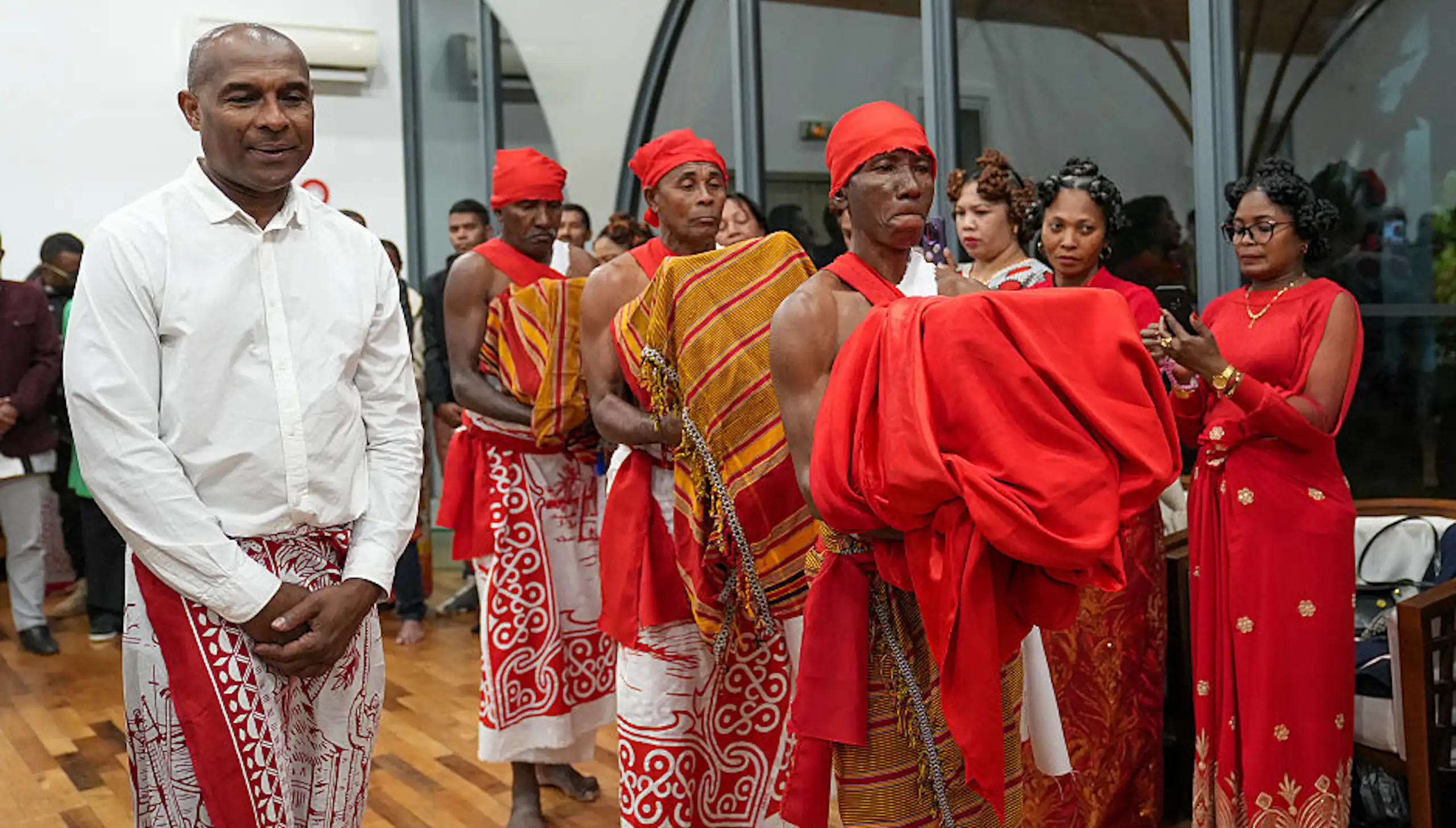 Three men carry draped bundles while other people look on