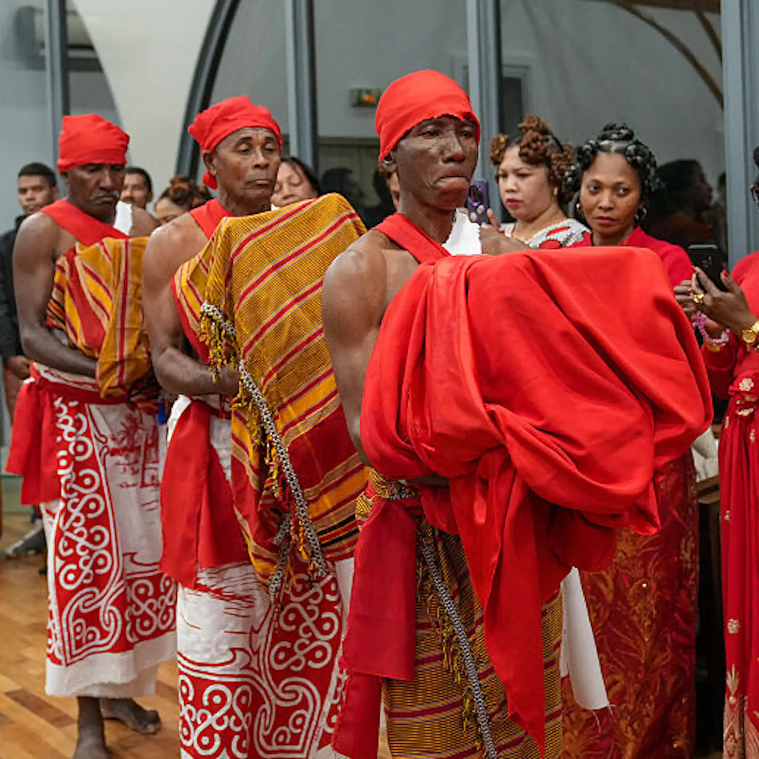 Three men carry draped bundles while other people look on