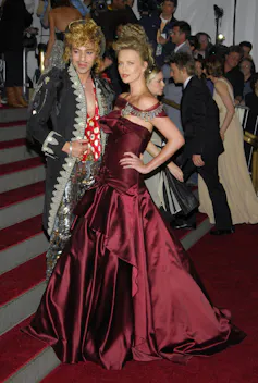 Un hombre y una mujer, ambos con vestidos de gala, posan en una alfombra roja.