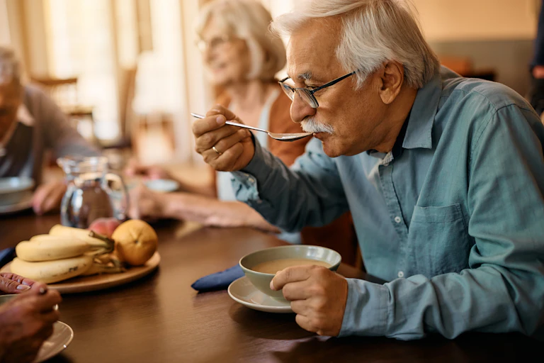 Older man eating soup.