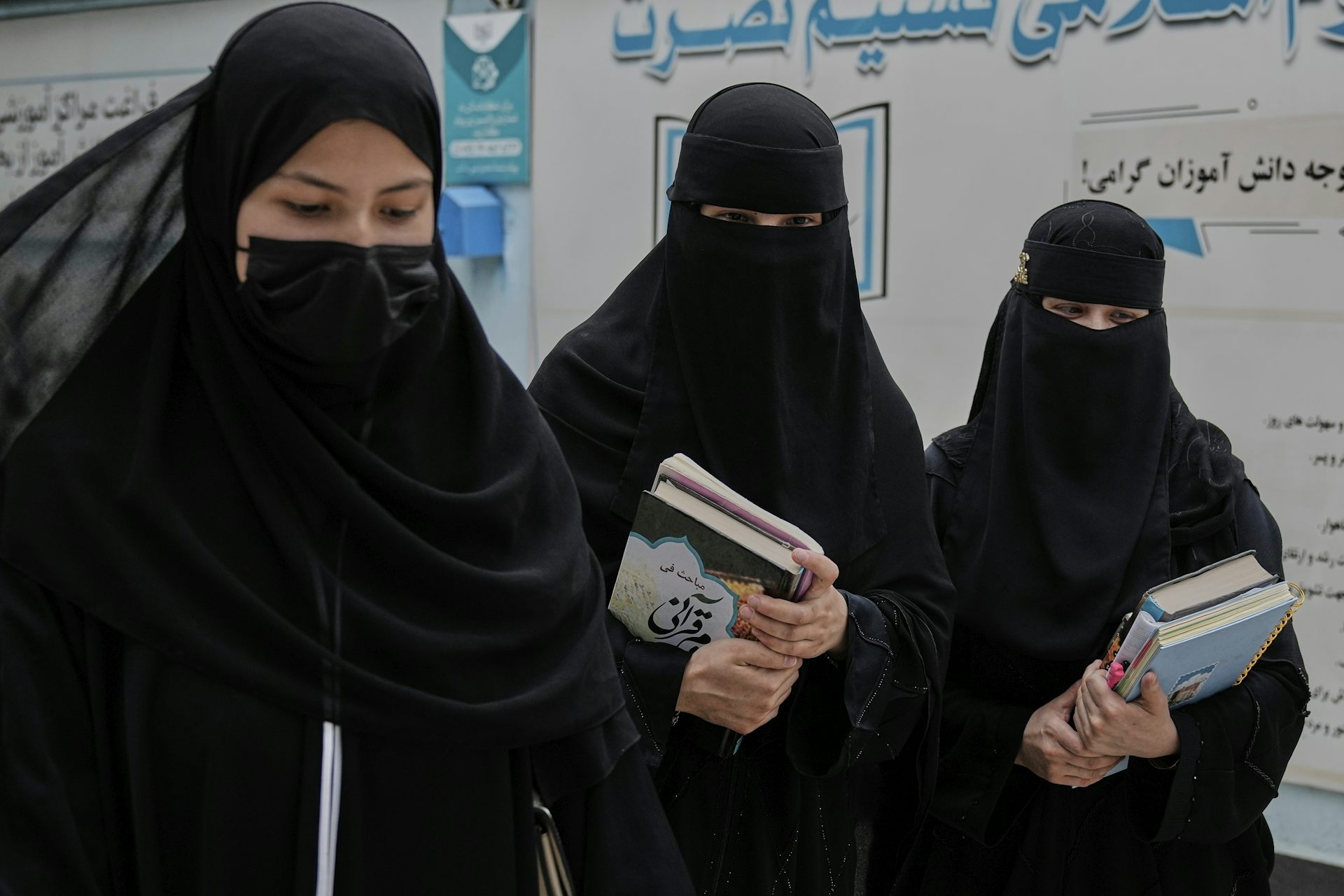 Three women walking with books in their hands.