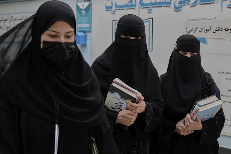 Three women walking with books in their hands.