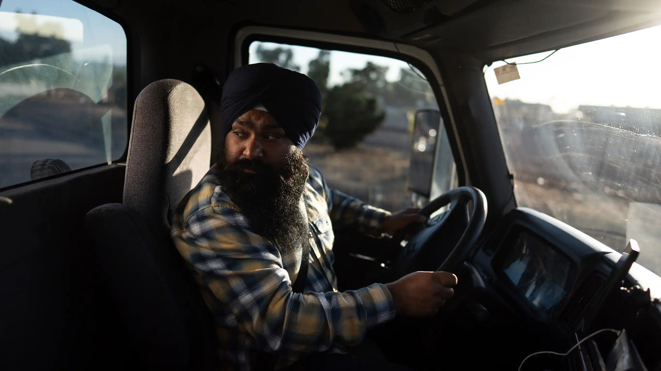 A sikh man in a turban in the cab of a truck