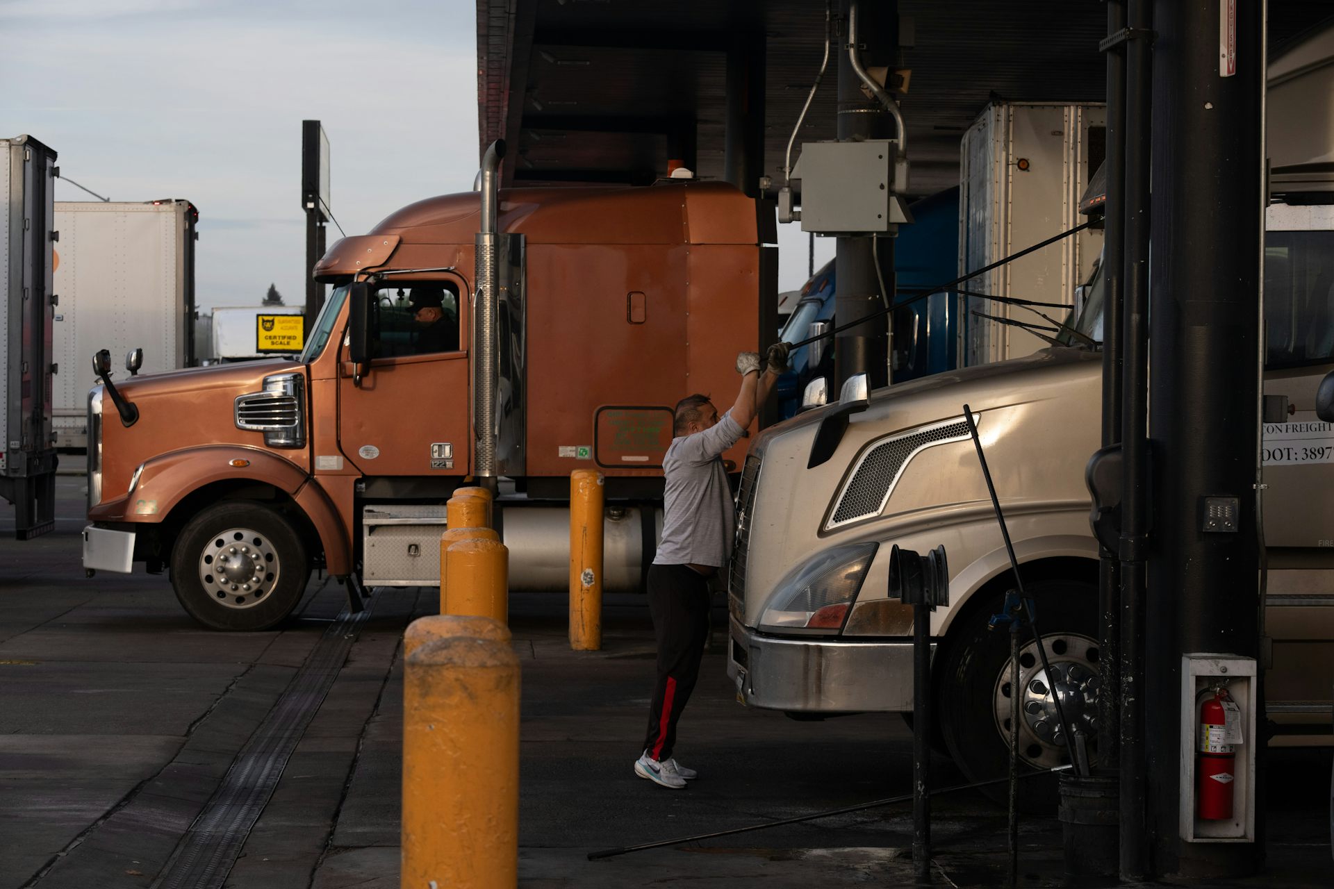 A trucker cleans the windshield while filing up a truck with fuel at a gas station