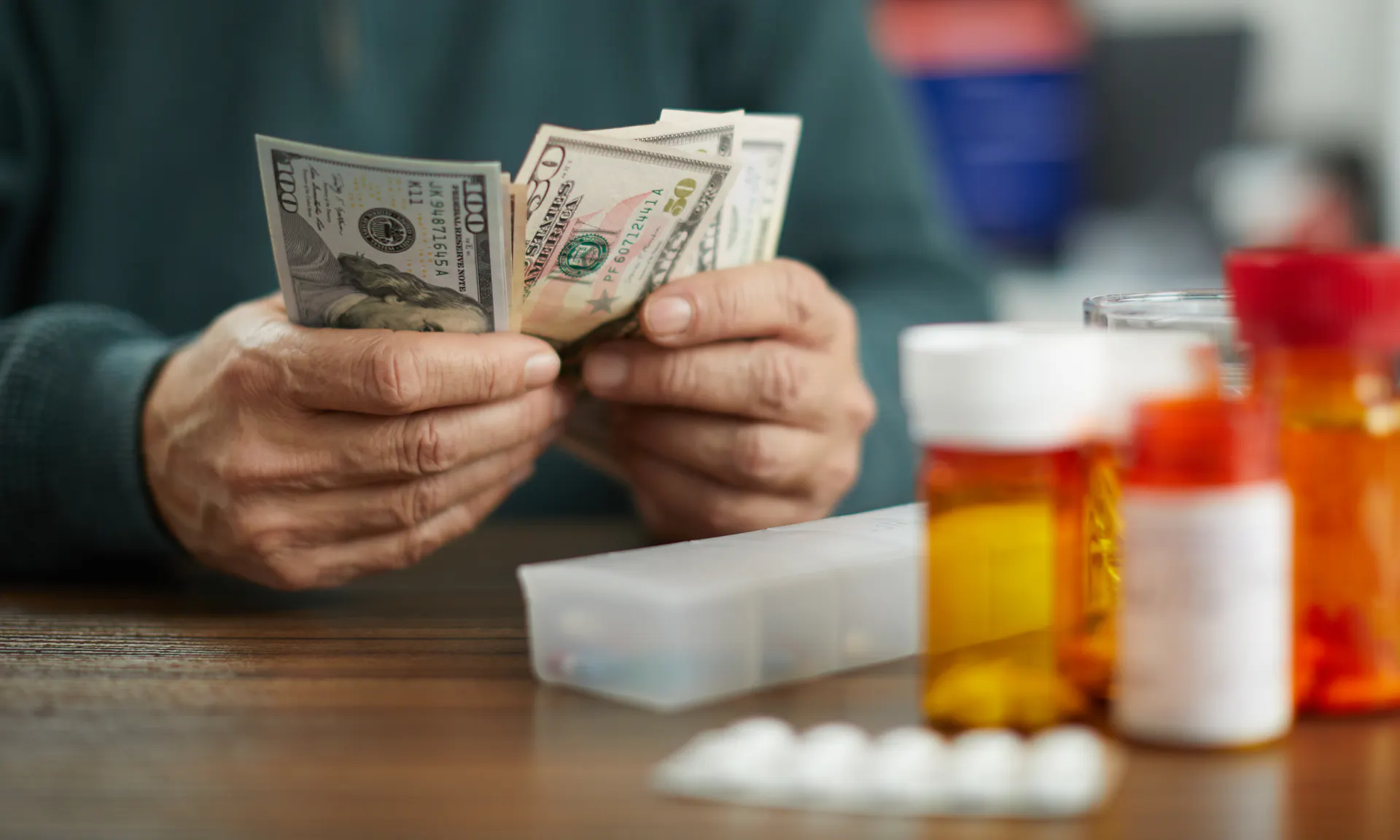 person counting cash next to a bunch of prescription bottles