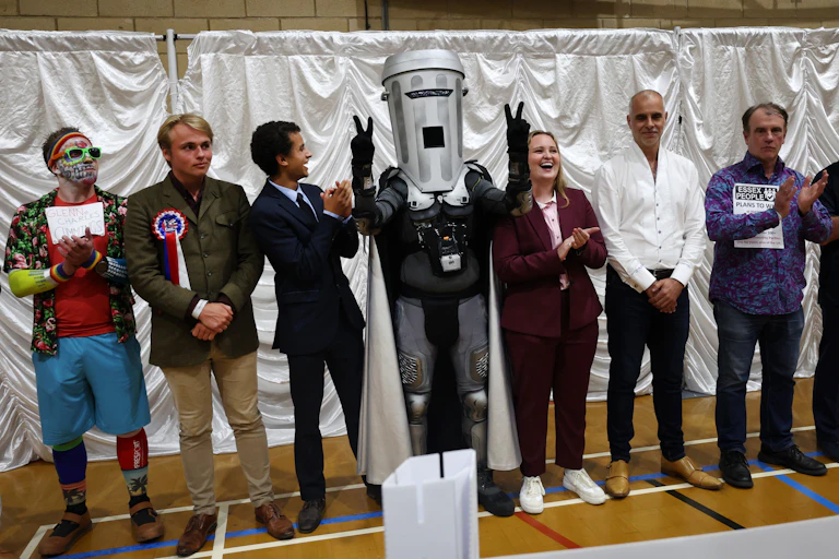 lineup of clacton candidates with count binface in the middle with his arms in the air.