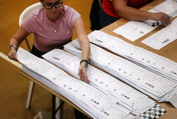 official at the clacton count laying out ballot papers that are more than one metre long.