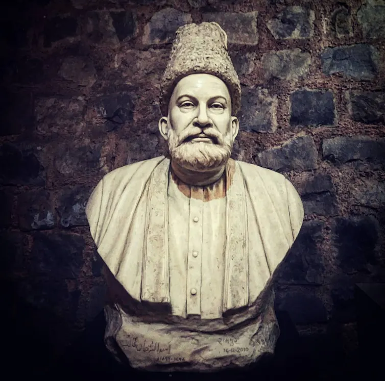 A stone bust of a man with a gray beard and mustache wearing a hat.