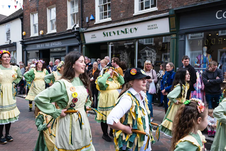 morris dancers in green and white outfits in an english high street