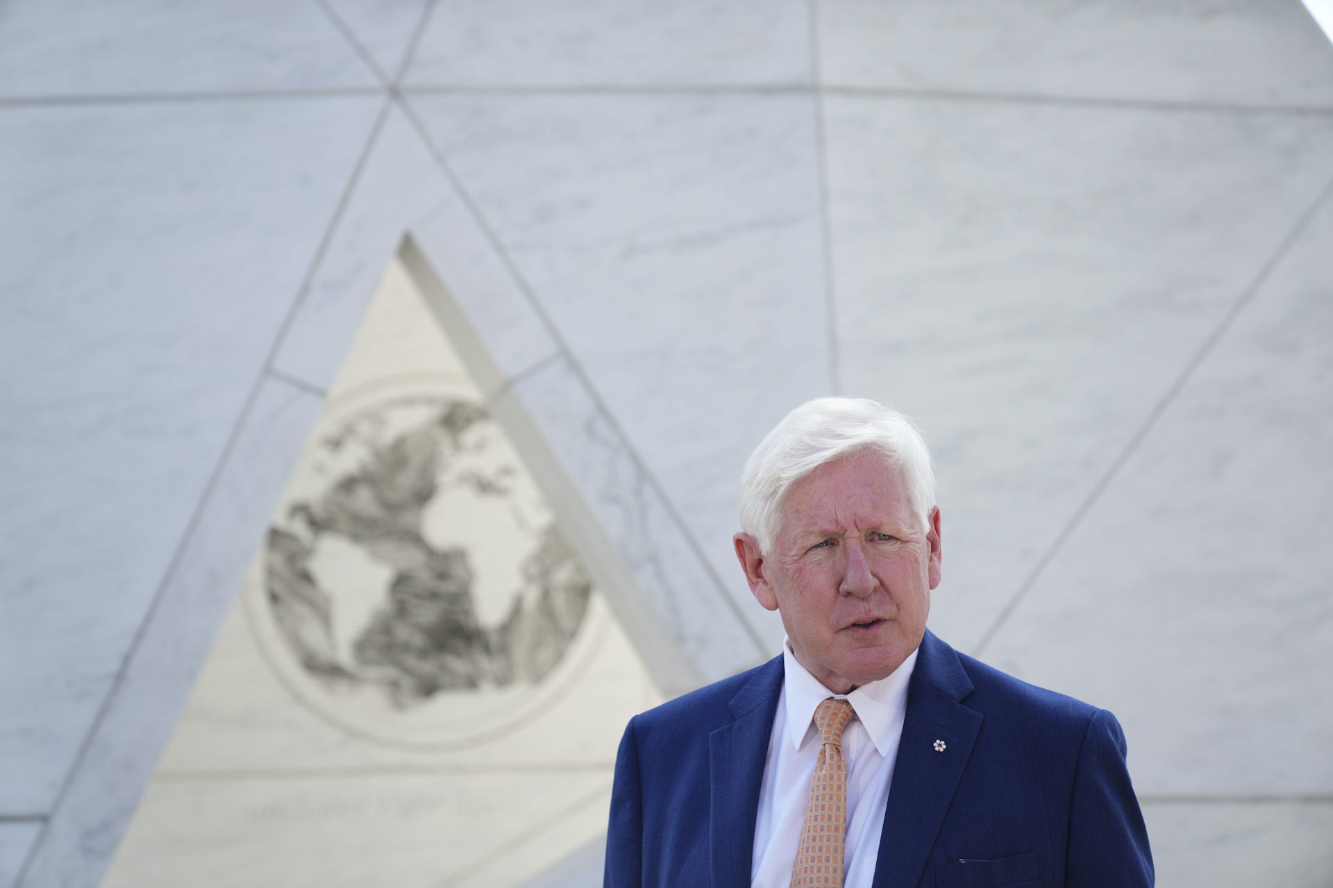 A man with white hair speaks in front of the UN.