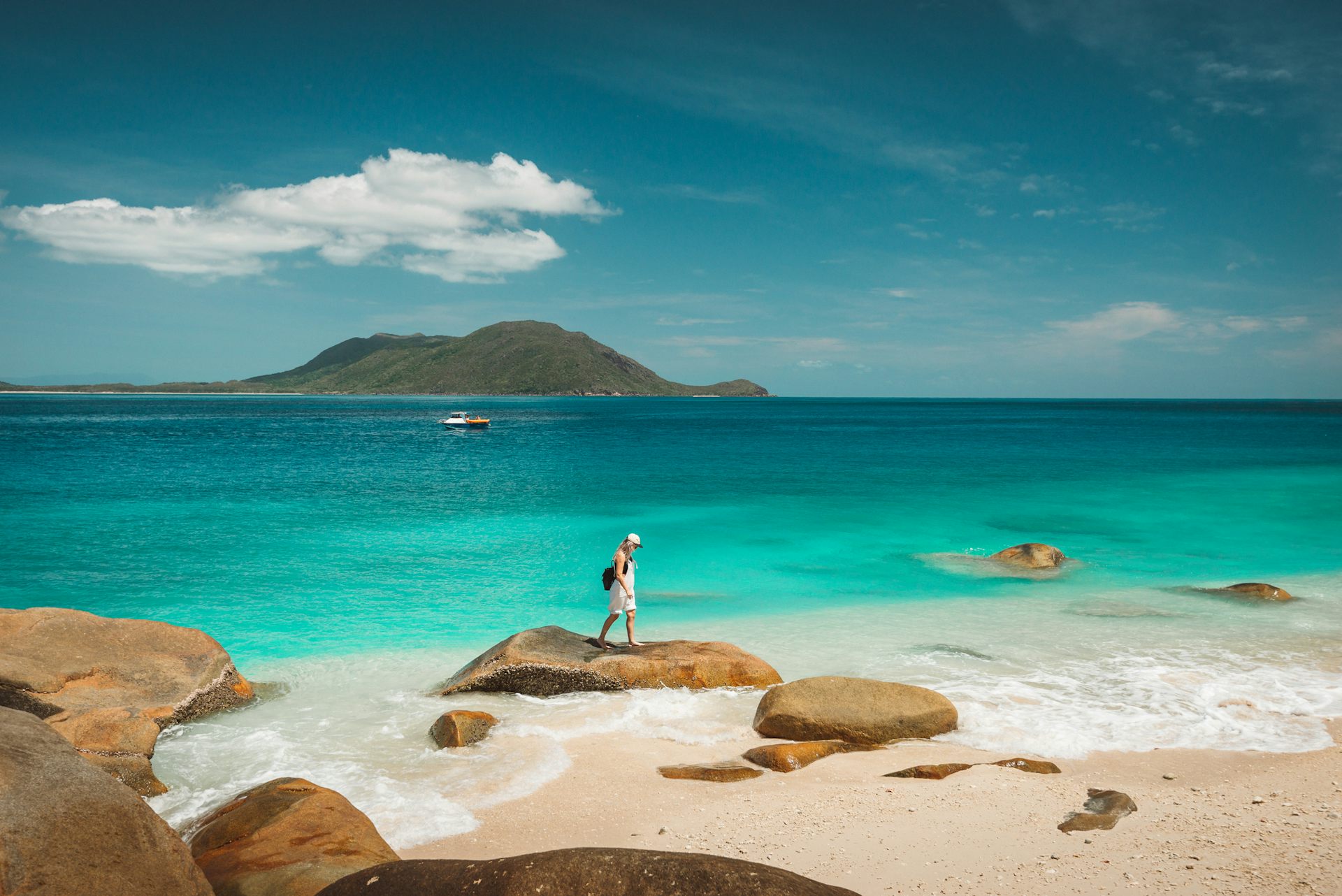 A woman looks at rock pools on a beach.