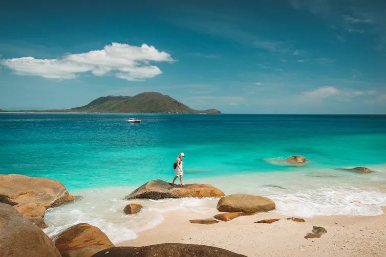 A woman looks at rock pools on a beach.