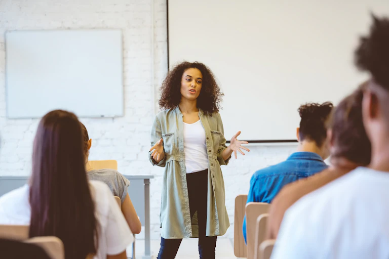 Female university student gesturing while speaking for class presentation.