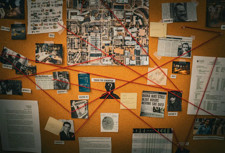 A board with pictures and documents pinned on it and red thread that connects them to each other.