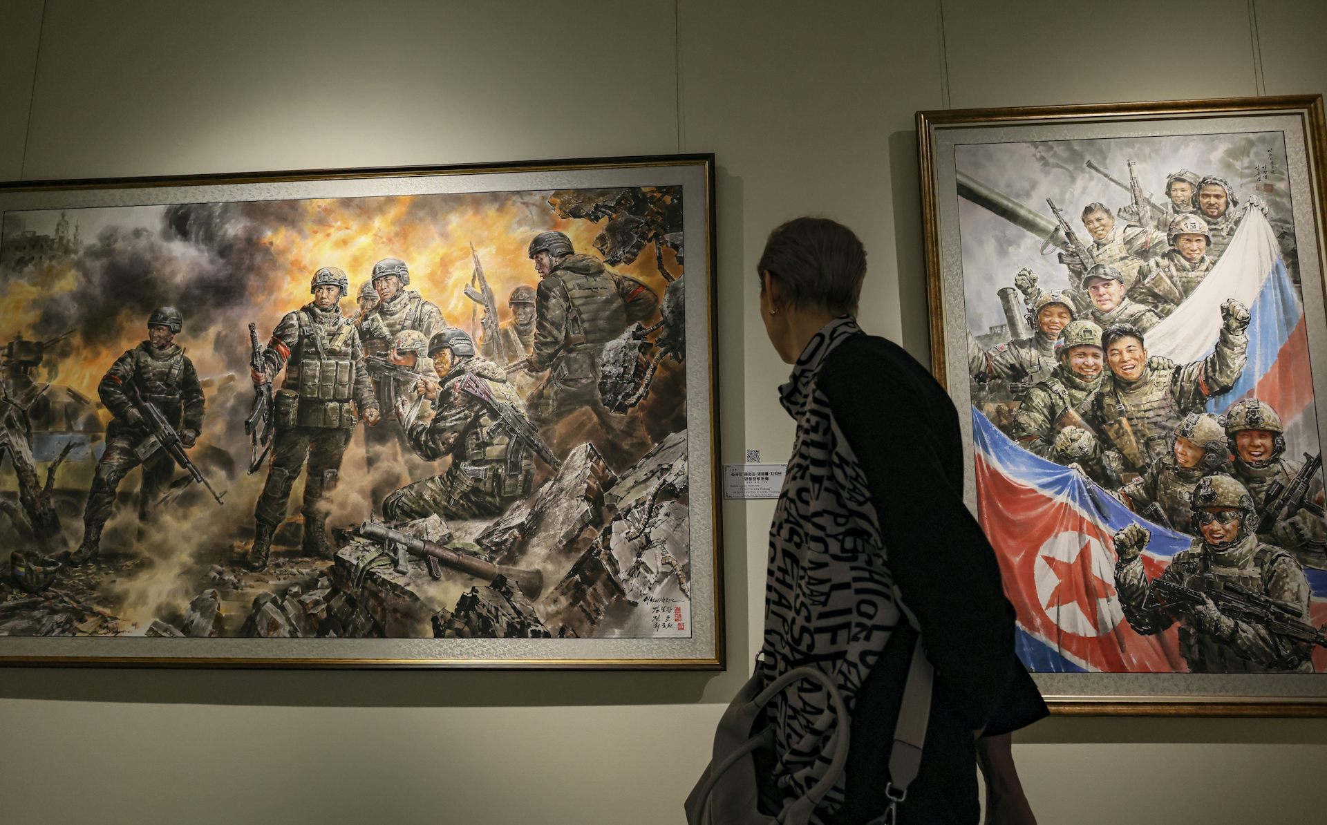 A visitor looks at paintings in an exhibition in Moscow celebrating the involvement of North Korean soldiers in the fighting in the Kursk region.