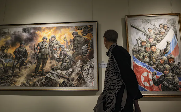 A visitor looks at paintings in an exhibition in Moscow celebrating the involvement of North Korean soldiers in the fighting in the Kursk region.