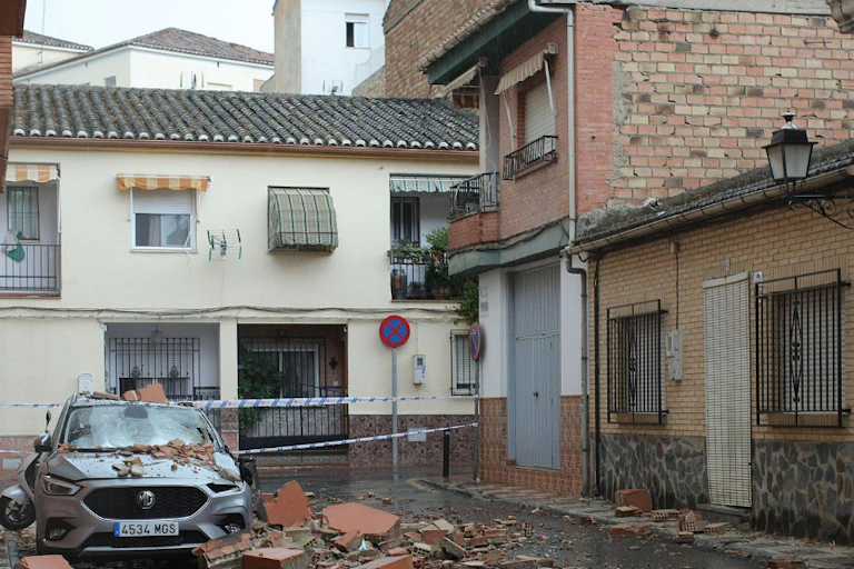 Un coche destrozado rodeado de cascotes.