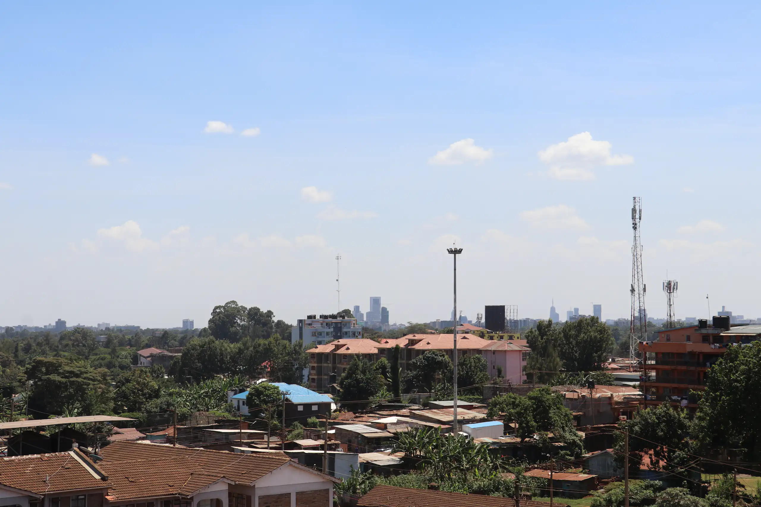 City skyline, with shacks in the foreground and tall buildings in the distance