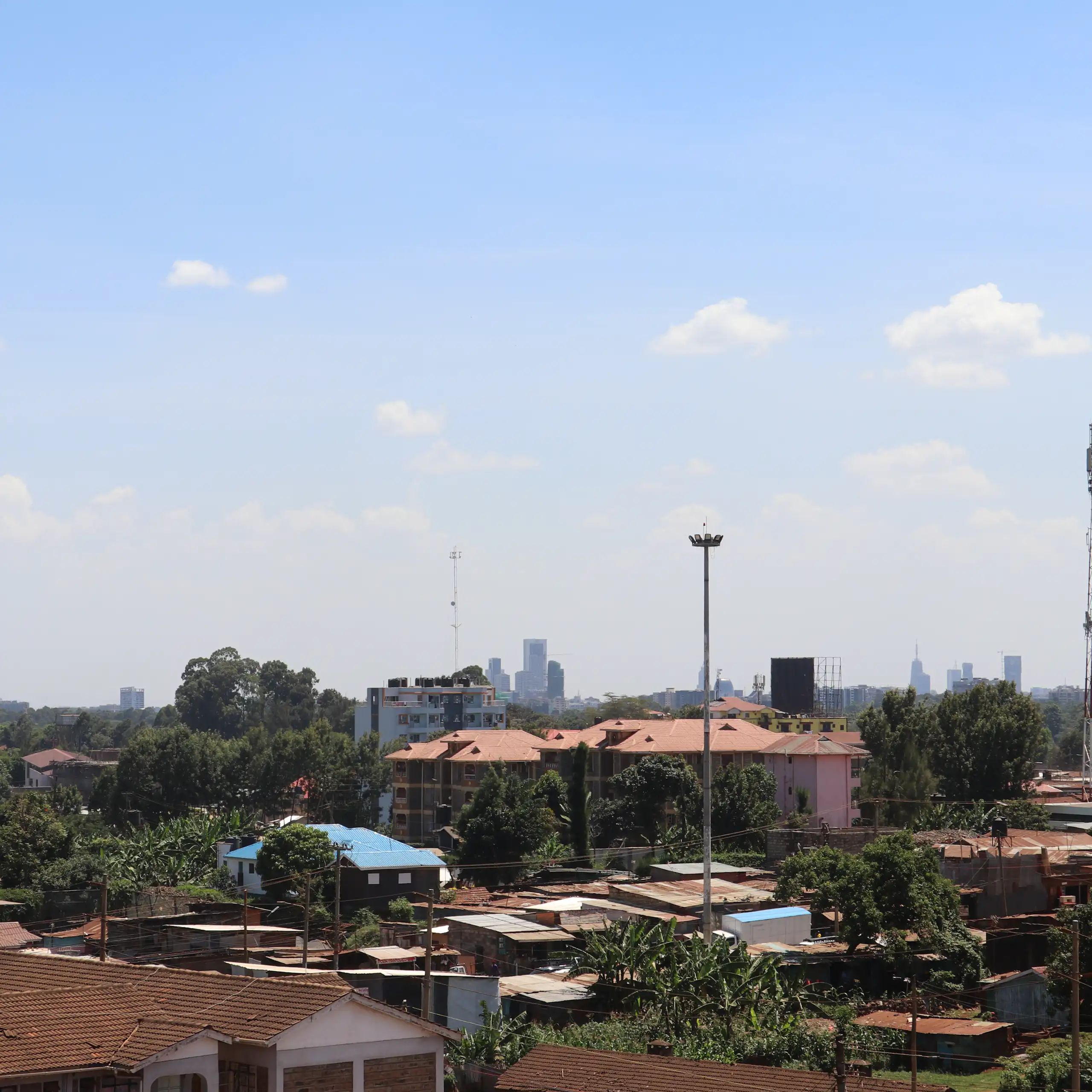 City skyline, with shacks in the foreground and tall buildings in the distance