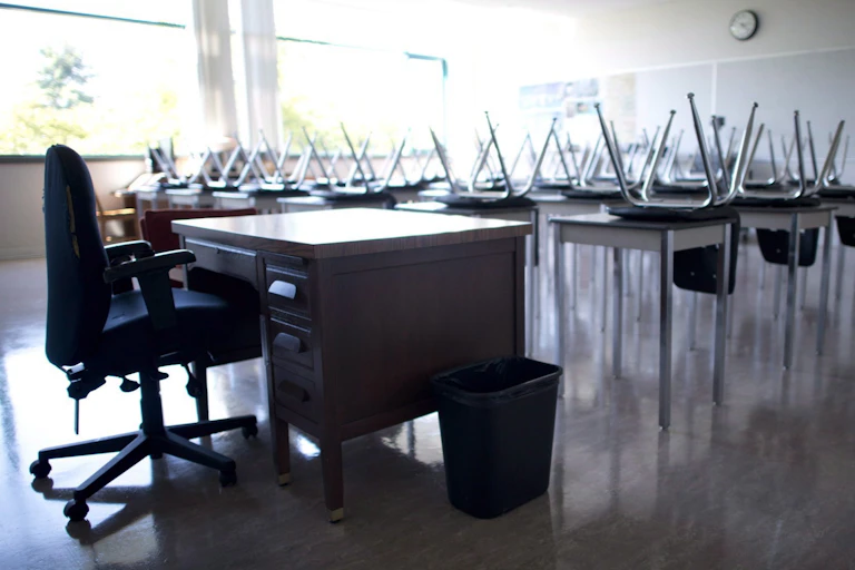 A classroom with empty desks and a teacher's chair.