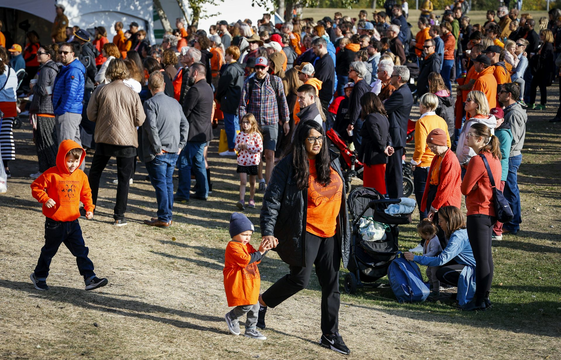 People of all ages walking with orange shirts on.