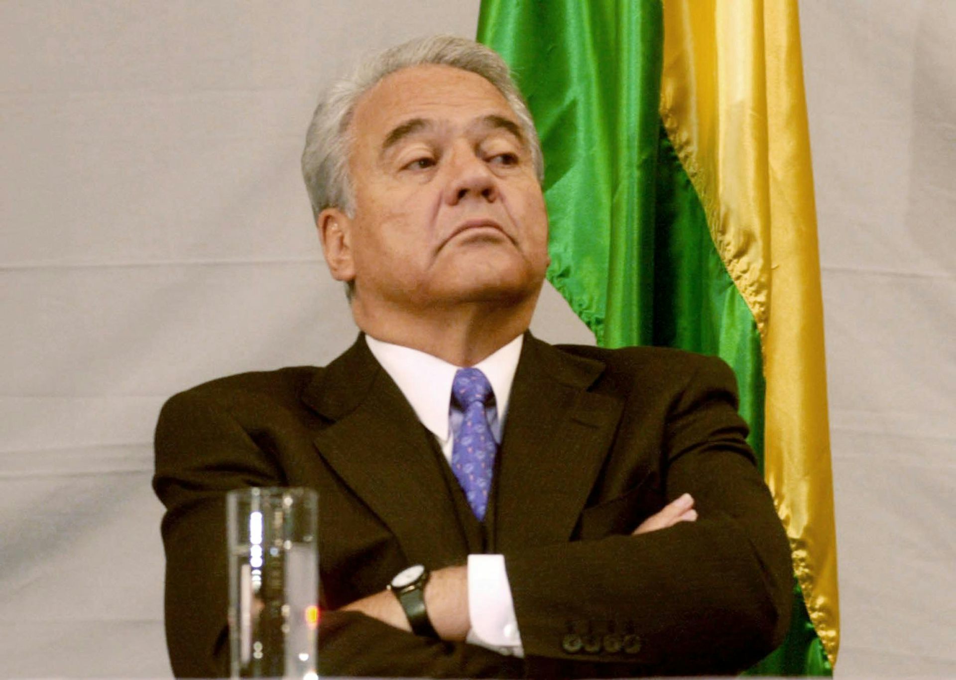A petulant looking grey-haired man with his arms crossed.