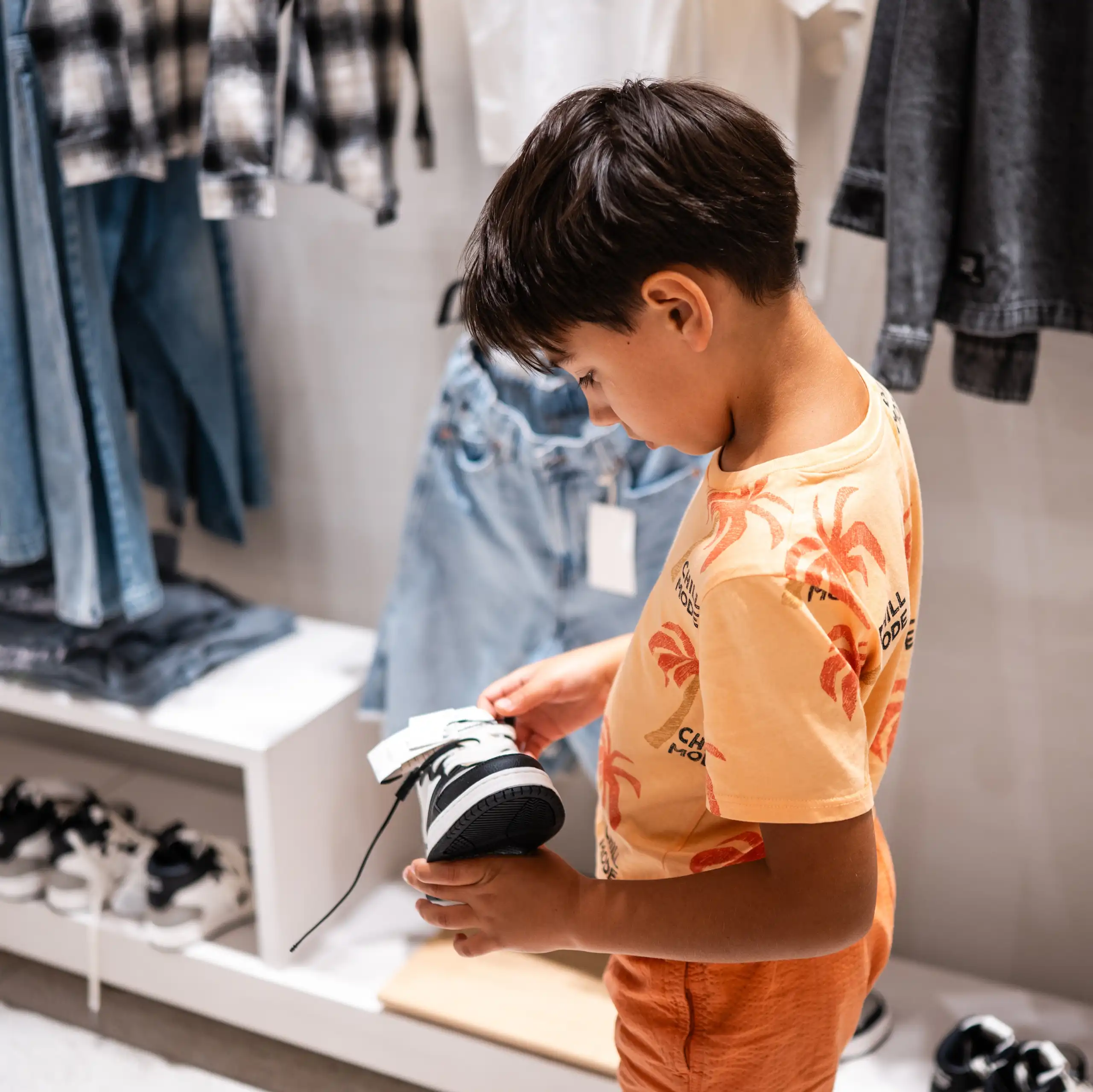 Un petit garçon examinant une basket dans un magasin.