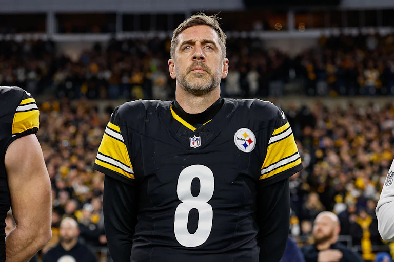 Aaron Rodgers, wearing his Steelers jersey, stands on a field.