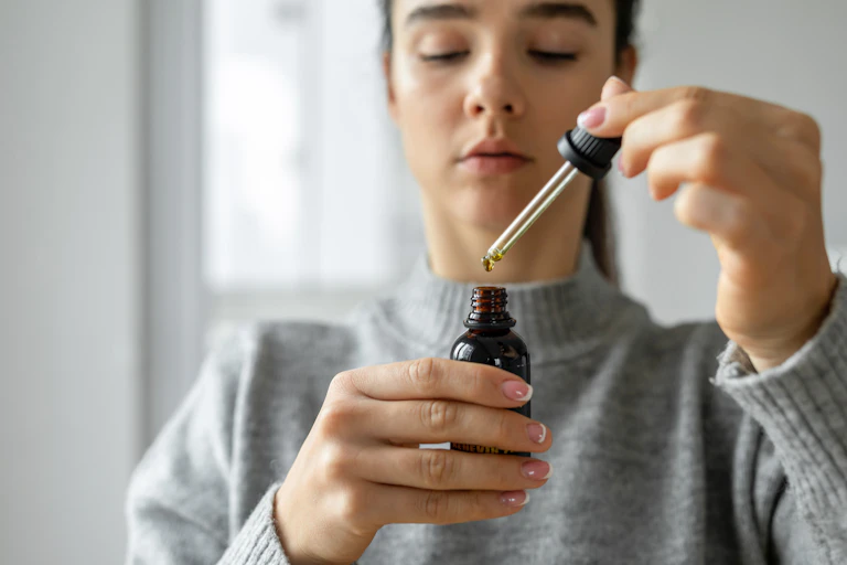 A young woman uses a dropper for cannabis oil