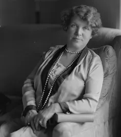 A woman, Ethel Turner, wearing pearls, looking serious.