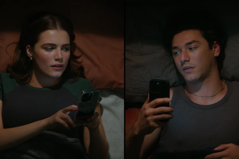 A divided frame shows a young woman and man using a smartphone in their respective beds.